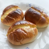 ロールパンの中央の切り込みにとろけたチーズが入っている写真