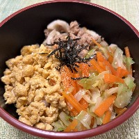 ツナと炒り卵とキャベツや人参がのった三色のそぼろ丼ぶりの写真