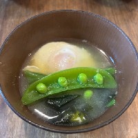 スナップエンドウと落とし卵、ワカメの入った味噌汁の写真