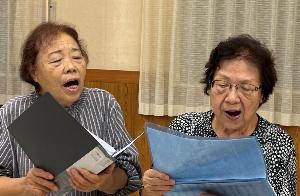 コーラス教室で元気に歌う80歳代女性2人の写真